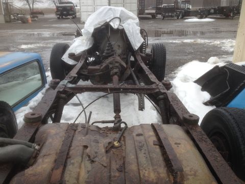 1979 Ford Bronco - The heavily rusted chassis and drivetrain of a vehicle, with a fuel tank prominently displayed in the foreground.