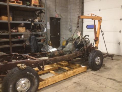 1979 Ford Bronco - The frame of a 1979 Ford Bronco is shown with its engine being lifted by an engine hoist.