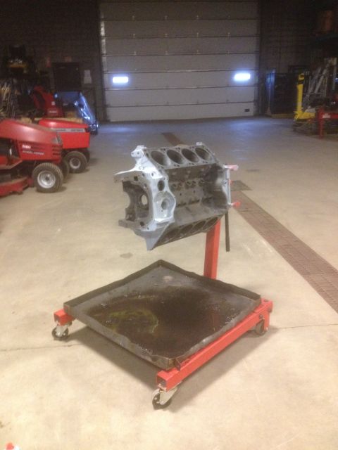 1979 Ford Bronco - An engine block sits on a red stand in a garage, with lawnmowers visible in the background.