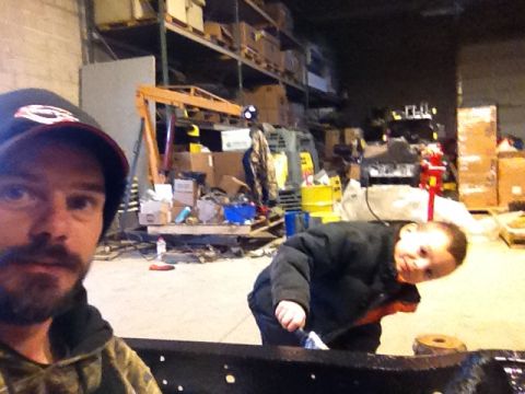 1979 Ford Bronco - A man and a child are in a workshop with storage shelves and equipment in the background.