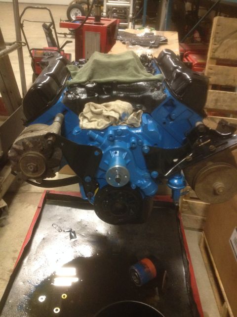 1979 Ford Bronco - Engine assembly with blue painted block and black valve covers sits in a workshop.