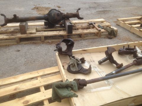 1979 Ford Bronco - Various rusty vehicle axle and suspension components are displayed on wooden pallets outdoors.