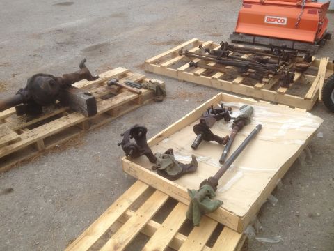 1979 Ford Bronco - Various vehicle axles and suspension components are organized on wooden pallets, ready for transport or storage.