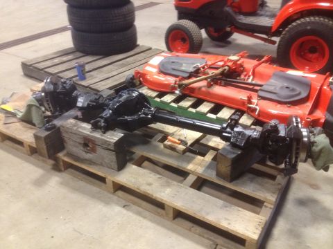1979 Ford Bronco - Vehicle axles and mower deck are disassembled and stored on pallets, with a tractor visible in the background.