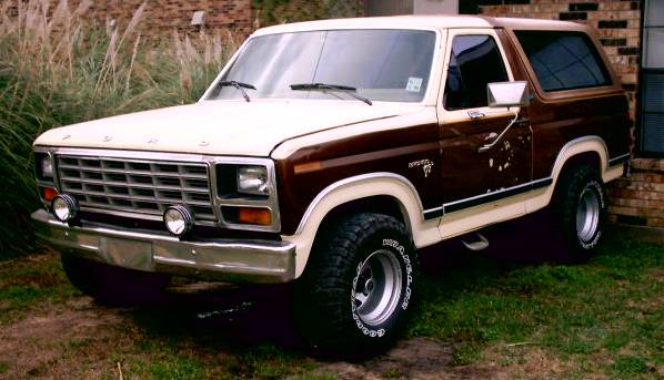 Two-tone brown and white 1980 Ford Bronco parked on grass