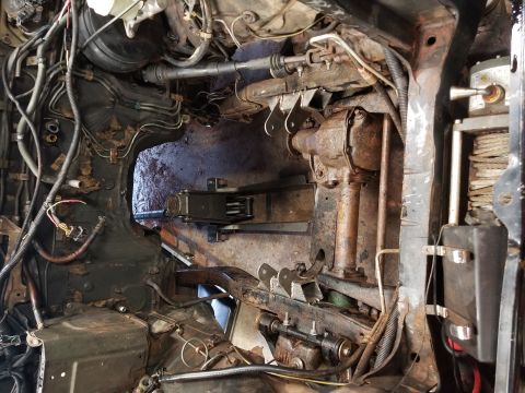 1991 Mitsubishi Montero - The complex, rusty undercarriage and engine bay of a vehicle are visible, with many wires and mechanical parts.