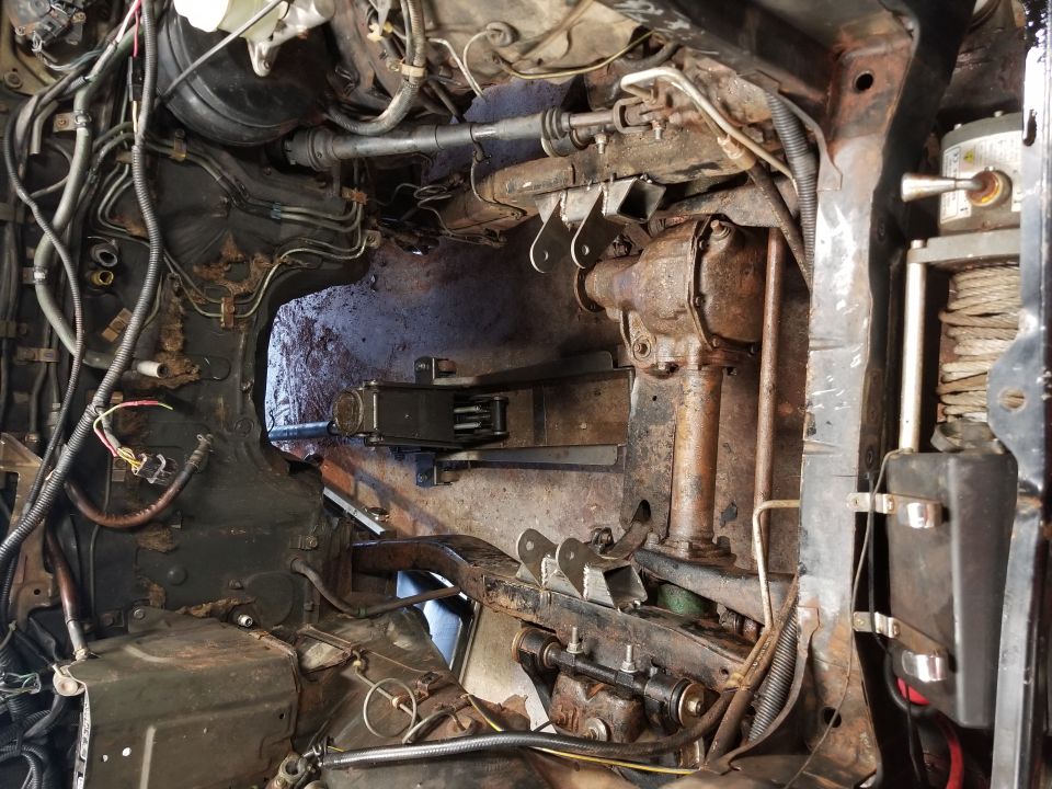 Undercarriage and engine bay of a vehicle, showing rusty components and wiring
