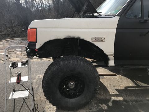 1989 Ford Bronco - Side view of a 1989 Ford F-250 truck undergoing repairs, showing the fender and wheel.