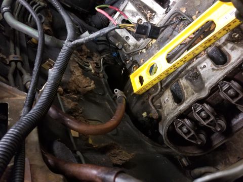 1991 Mitsubishi Montero - A yellow bubble level is placed on the engine's valve cover, likely for a repair or diagnostic check.