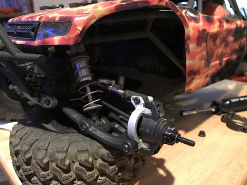 1989 Ford Bronco - Close-up of an RC car's front suspension and wheel assembly, with a flame graphic on the body.