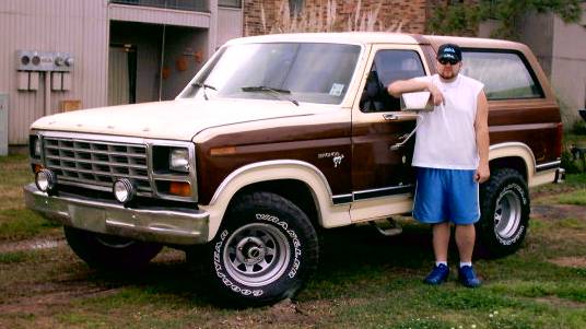 Man leaning on a two-tone brown and white Ford Bronco