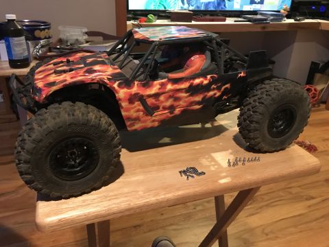 1989 Ford Bronco - A remote control rock crawler with a flame graphic body sits on a table next to small screws.