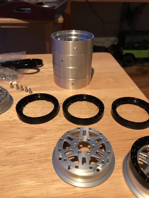 1989 Ford Bronco - Several unassembled RC car wheel components are arranged on a table, with a small green RC vehicle in the background.