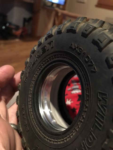 1989 Ford Bronco - A person holds a detailed RC car tire, showing its aggressive tread pattern and aluminum rim.