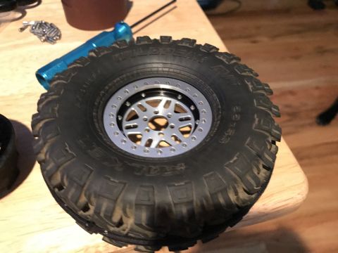 1989 Ford Bronco - A close-up of a tire and wheel assembly, likely for an RC car, rests on a table.