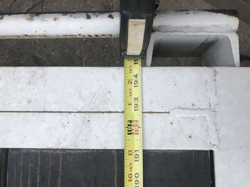 Measuring tape showing 193 inches on a white metal frame with rust spots