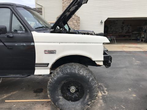 1989 Ford Bronco - This truck has a two-tone paint job and is undergoing some work, with the hood open and front bumper removed.