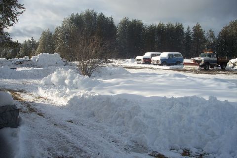 1973 Ford F-250 - Several vehicles, including trucks and a van, are parked in a snowy landscape, with one truck equipped with a snowplow.