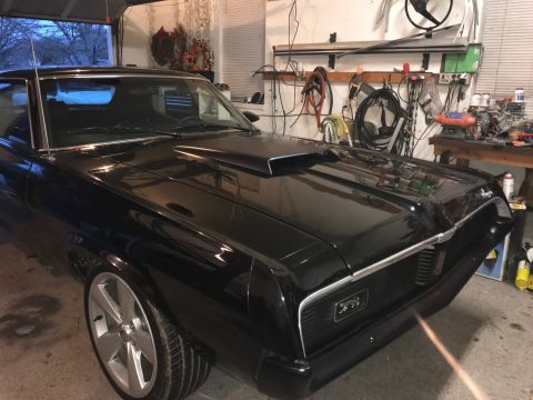 1969 Mercury Cougar - Black 1969 Mercury Cougar with a hood scoop is parked inside a garage with tools on the wall.