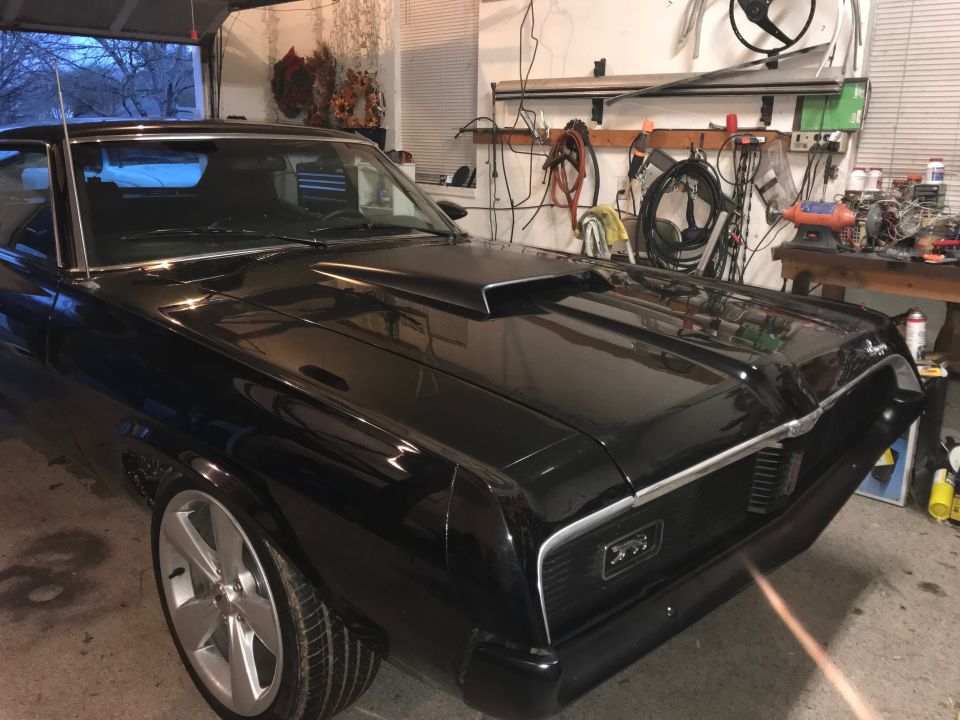 Black 1969 Mercury Cougar with a hood scoop parked in a garage
