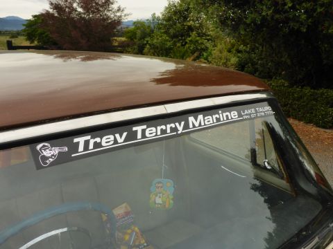 1962 MG B - Interior view of a brown vehicle a 'Trev Terry Marine' decal on the windshield.