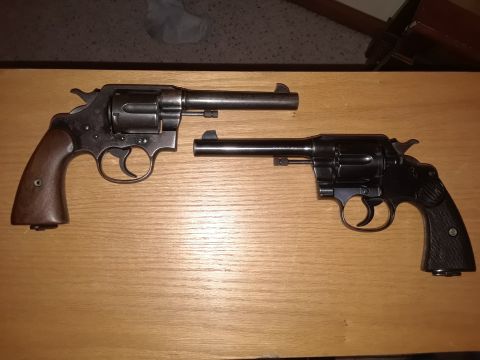 1994 Ford Bronco - Two revolvers are displayed on a wooden table, with one slightly behind the other.