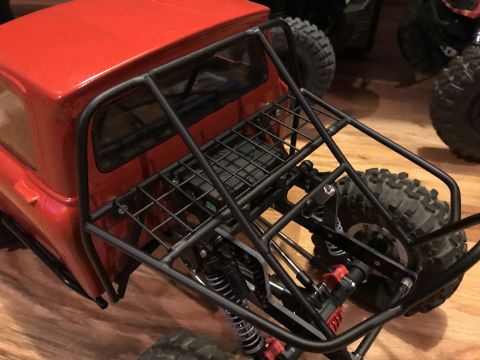 1989 Ford Bronco - Close-up of a red RC rock crawler truck's rear, a roll cage and suspension components.