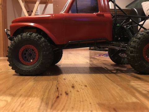 1989 Ford Bronco - Side view of a red RC truck with aggressive tires and a visible roll cage.