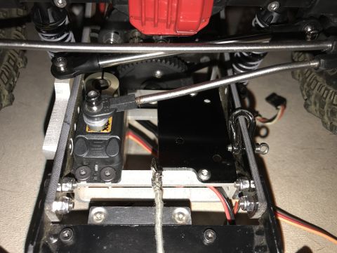 1989 Ford Bronco - Close-up view of the undercarriage of a remote control car, showing the servo motor, suspension components, and drivetrain.