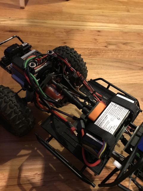 1989 Ford Bronco - The internal components and chassis of a remote control car are visible, with wires and a battery pack secured to the right.