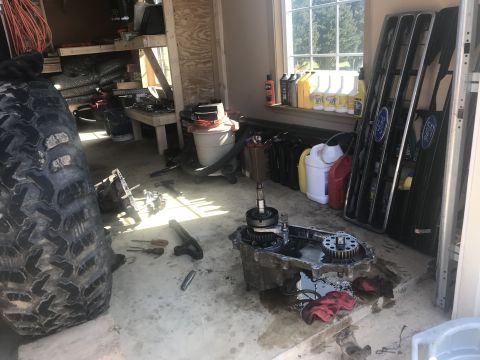 1989 Ford Bronco - Disassembled transfer case and Ford Bronco grille are visible in a garage setting with various fluids and tools.