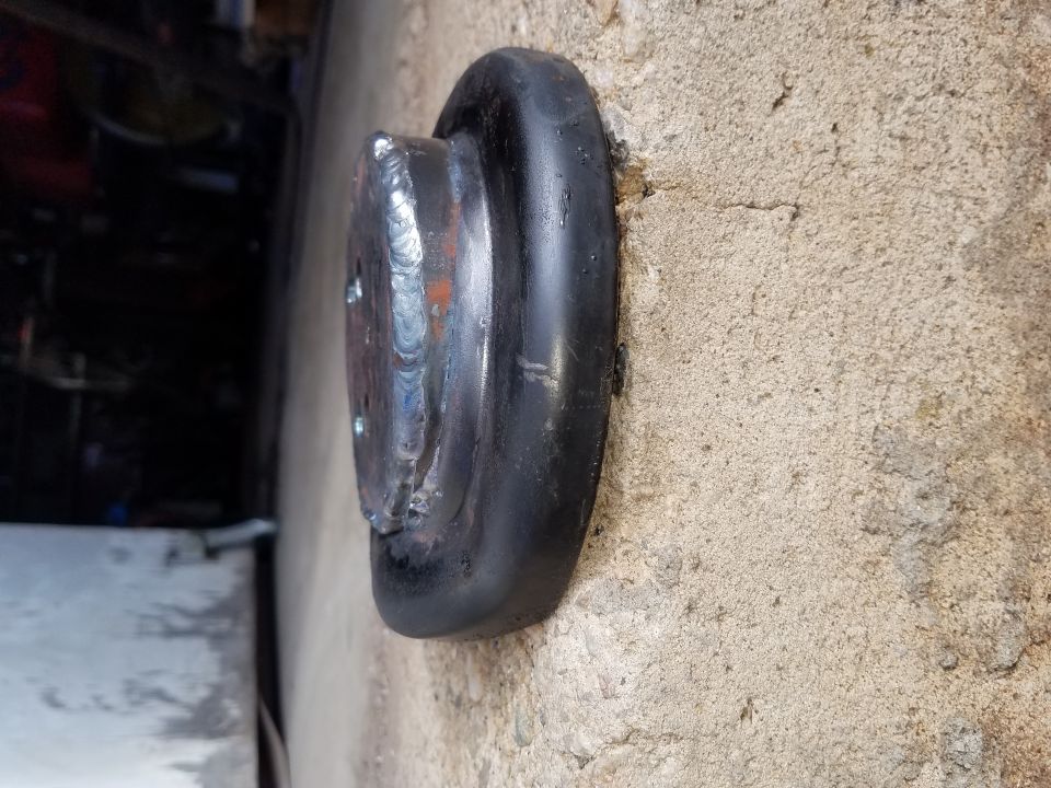 welded metal disc with rubber trim attached to concrete wall