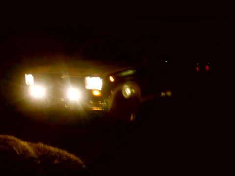 1980 Ford Bronco - The front of a 1980 Ford Bronco is visible at night, illuminated by its headlights.