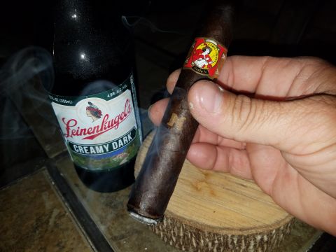2018 Ford Bronco - A hand holds a smoking cigar beside a bottle of Leinenkugel's Creamy Dark beer, suggesting a moment of relaxation.