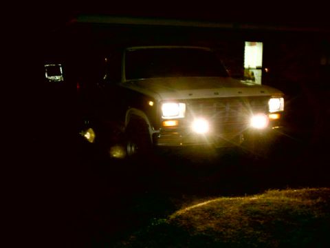 1980 Ford Bronco - Front view of a 1980 Ford Bronco at night, headlights illuminated.