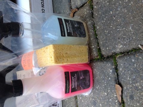 1995 Ford Bronco - Car cleaning supplies including floor mat cleaner and protector bottles and a sponge.