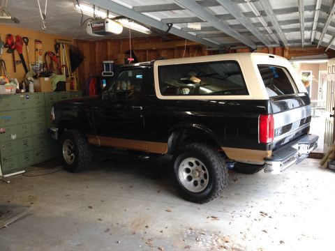 1995 Ford Bronco - This Ford Bronco is parked inside a garage with tools and storage units visible.