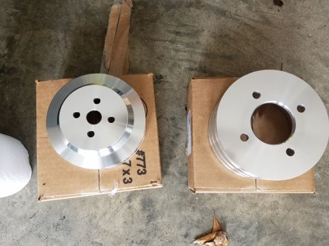 1976 Ford Ranchero - Two aluminum pulleys are shown, one with four bolt holes and the other with three grooves, resting on cardboard boxes.