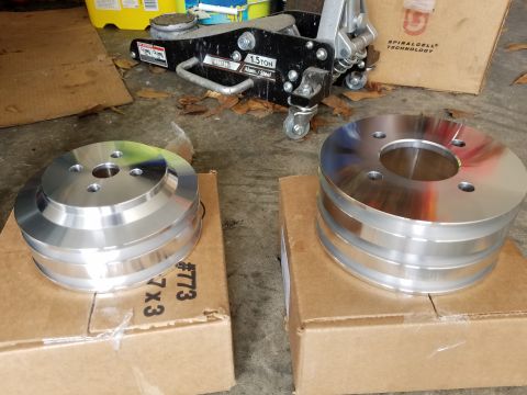 1976 Ford Ranchero - Two aluminum pulleys are shown on cardboard boxes, with a floor jack and other items in the background.