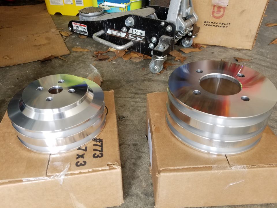 Two aluminum pulleys on cardboard boxes with a floor jack in the background