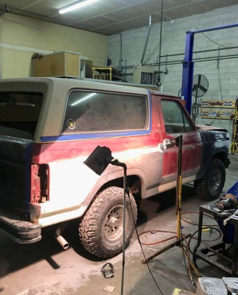 1985 Ford Bronco - Ford Bronco in a workshop, possibly undergoing rust repair or body modification.