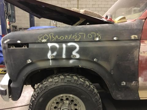 1985 Ford Bronco - A Ford Bronco's fender is prepped for bodywork, with handwritten markings indicating project details.