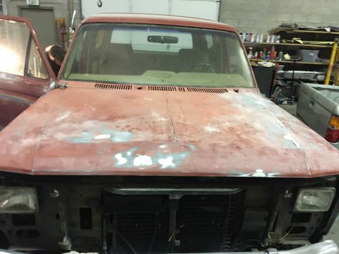 1985 Ford Bronco - This 1985 Ford Bronco is in a garage, likely for rust repair, showing its front end with the hood open.