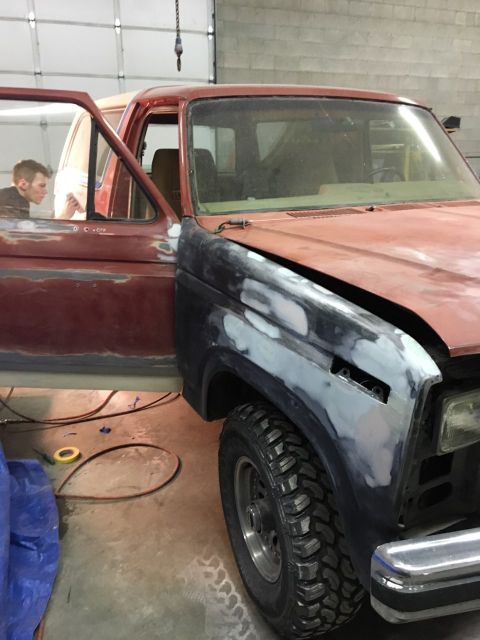 1985 Ford Bronco - Ford Bronco in shop for rust repair, showing bodywork in progress on the front fender.
