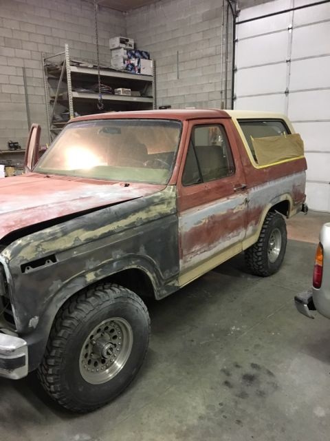 1985 Ford Bronco - A classic Ford Bronco is shown in a garage, with its front end prepped for paint and bodywork.