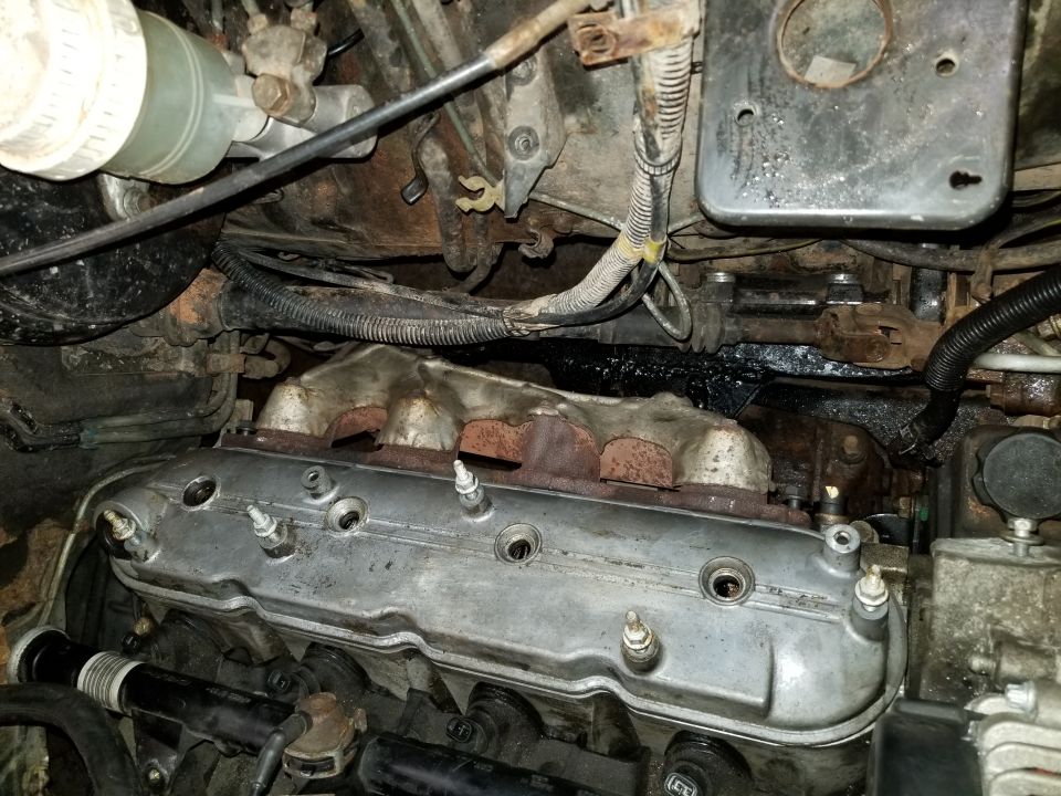 Engine bay with valve covers, exhaust manifolds, and brake fluid reservoir visible