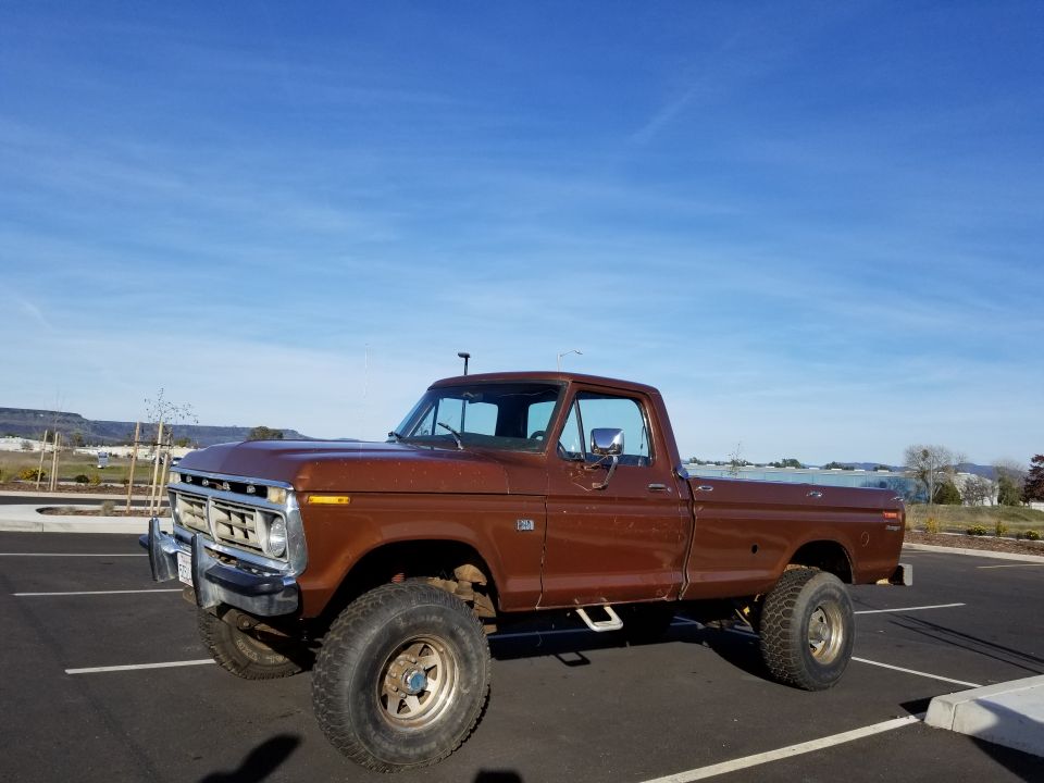 Brown lifted 1970s Ford F-250 pickup truck parked in a lot.