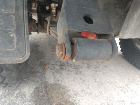 1989 Ford Bronco - A close-up view of the rear suspension of a 1989 Ford Bronco shows a rusty leaf spring shackle with a bolt and bushing. The tire and part o…