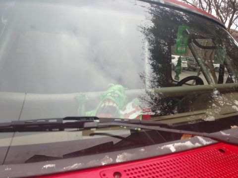 1989 Ford Bronco - A green ghost toy is visible through the windshield of a red vehicle, sitting on the dashboard. A green air freshener hangs from the rearvi…