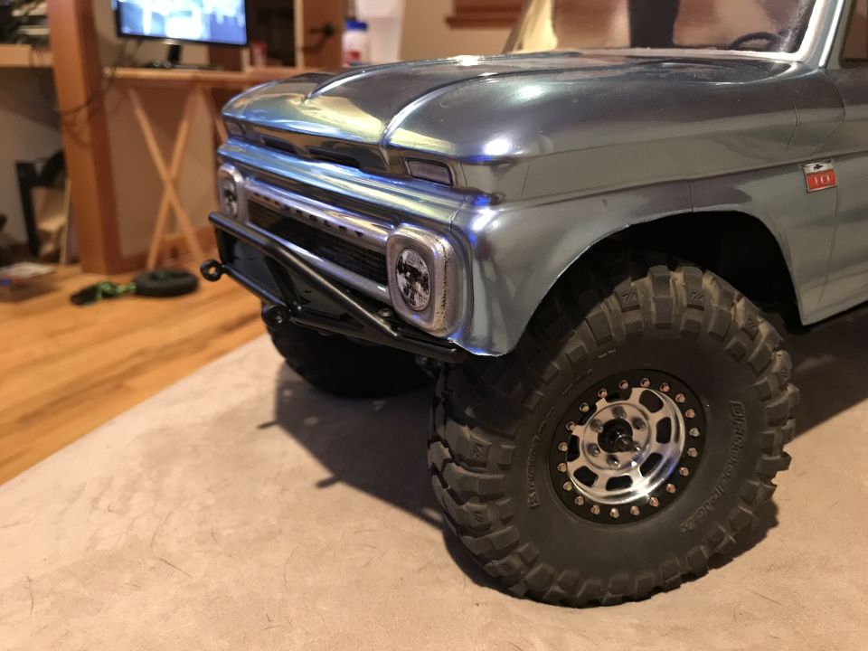 Metallic blue pickup truck front right corner with off-road tires and black bumper.